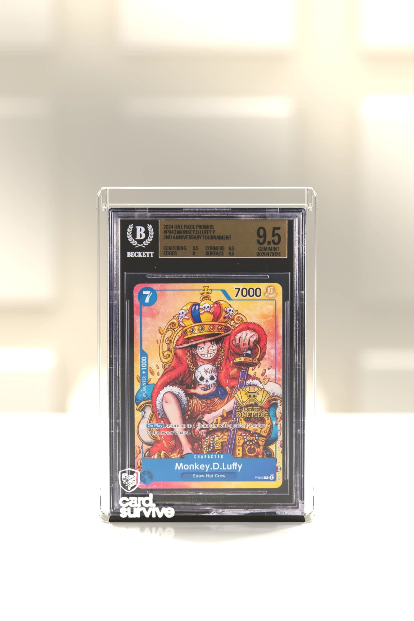 The Tank with a Beckett slab of Monkey D. Luffy inside, front view, on a white showcase in a boutique display, cream light.